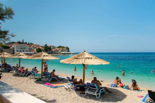 a group of people sitting on a beach with umbrellas at Apartment Murva in Primošten