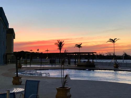 uma piscina com palmeiras e um pôr-do-sol ao fundo em GOLDEN LAKE, lugar para relaxar em Arraial do Cabo