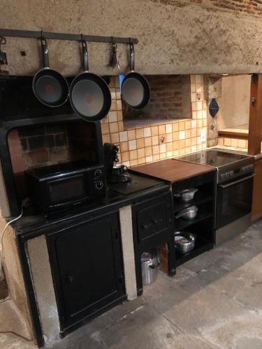 une cuisine avec une cuisinière et quelques casseroles et poêles dans l'établissement Chateau de Grand Bonnefont, à Limoges