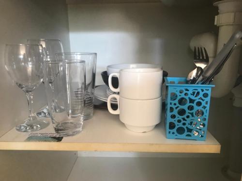 a shelf with glasses and other glass items on it at Blue Pelican Motel in Tweed Heads