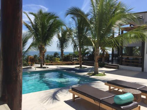 a swimming pool with palm trees and a house at Mar de Mancora Playa Las Pocitas in Máncora