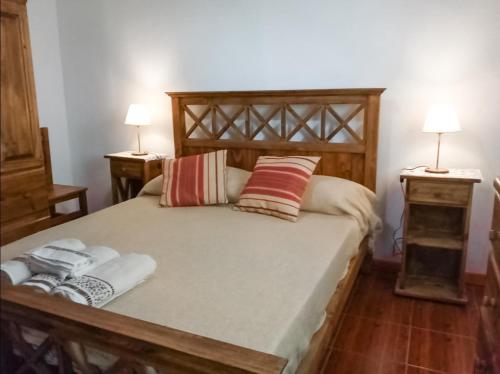 um quarto com uma cama de madeira e 2 mesas de cabeceira em Alojamiento Las Retamas em El Bolsón