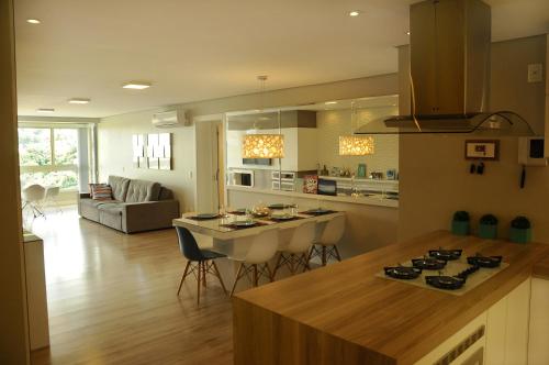 a kitchen and living room with a counter and a table at Apto Novo e Moderno no Centro de Gramado in Gramado