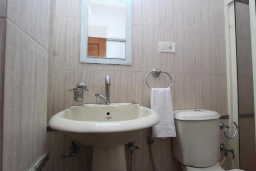 a bathroom with a sink and a toilet and a mirror at Bluemoon Grand in Bangalore