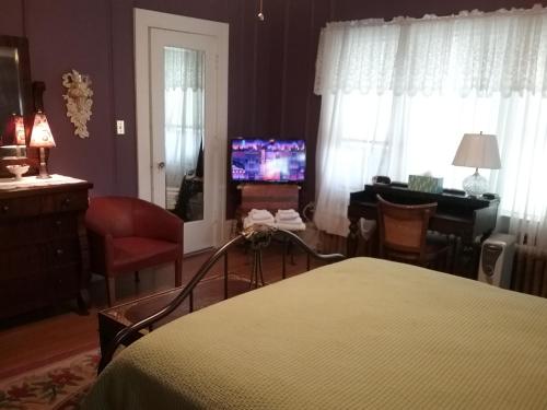 a bedroom with a bed and a desk and a television at Hanover House Bed and Breakfast in Niagara Falls