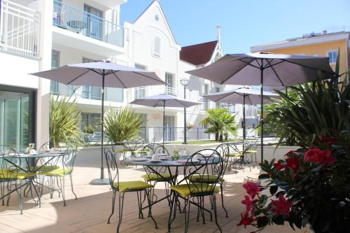 Residhome Arcachon Plazza في أركاشون: فناء في الهواء الطلق مع طاولات وكراسي ومظلات