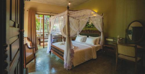 a bedroom with a bed with a canopy at Ayur Ayur Resort & Ayurveda Retreat in Negombo