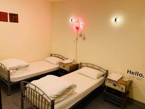 three beds in a room with hello sign on the wall at Skyone Hotel in Kaohsiung