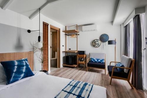 a hotel room with a bed and a tv and chairs at HOMM Boutique Hotel in Chiang Mai