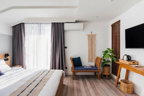 a bedroom with a bed and a tv and a chair at HOMM Boutique Hotel in Chiang Mai