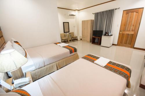 a hotel room with two beds and a desk at Sur Beach Resort Boracay in Boracay
