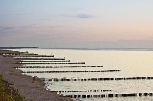a row of benches in the water on a beach at Apartamenty Na Klifie in Ustronie Morskie