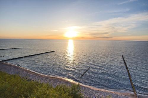 a sunset over a body of water with a pier at Apartamenty Na Klifie in Ustronie Morskie