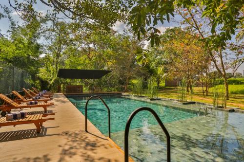 a swimming pool with chairs and a swimming pool at Kalundewa Retreat in Dambulla