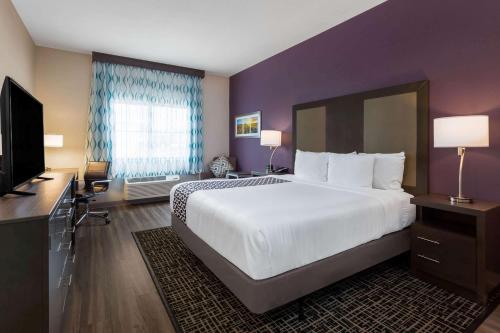 a hotel room with a large bed and a television at La Quinta by Wyndham Wichita Airport in Wichita
