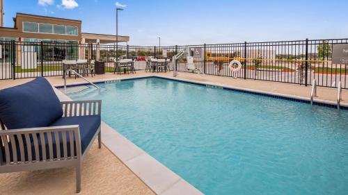 a swimming pool with a blue chair next to a fence at Best Western Plus Executive Residency Austin - Round Rock in Austin