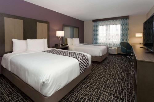 a hotel room with two beds and a television at La Quinta by Wyndham Wichita Airport in Wichita