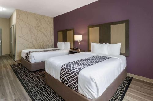 two beds in a hotel room with purple walls at La Quinta by Wyndham Wichita Airport in Wichita