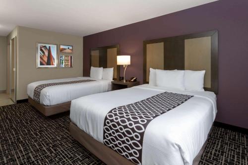a hotel room with two beds with white sheets at La Quinta by Wyndham Wichita Airport in Wichita