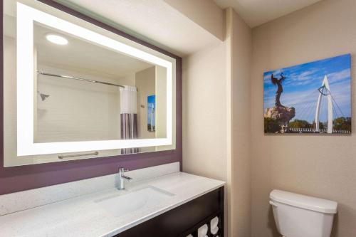 a bathroom with a sink and a picture of a giraffe at La Quinta by Wyndham Wichita Airport in Wichita