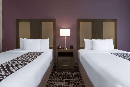 two beds sitting next to each other in a hotel room at La Quinta by Wyndham Wichita Airport in Wichita