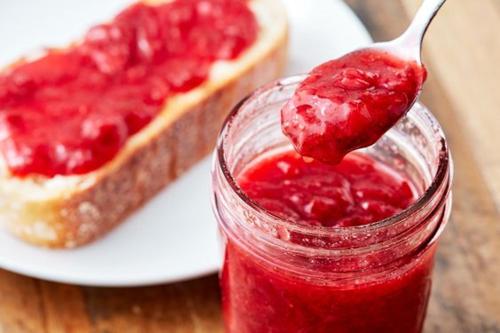 a spoon in a jar of raspberry jam next to a pie at Past Tense Hostel in Chiang Mai