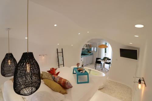 a white living room with a couch and a tv at Naxos Cave Suites in Stelida