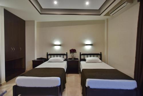 two beds in a hotel room with flowers on the wall at 24 Seven Boutique Hotel in Malia
