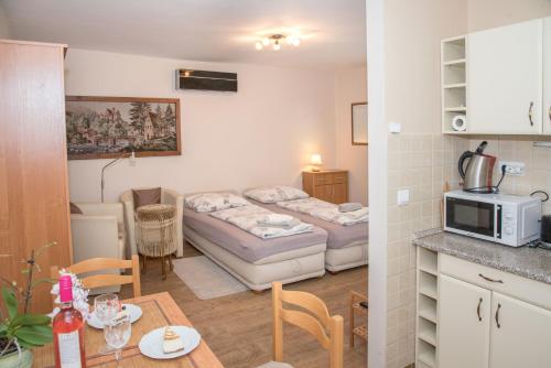 Habitación con 2 camas y cocina con mesa. en Deluxe Apartments, en Hévíz