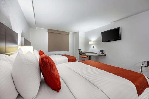 a hotel room with two beds and a flat screen tv at BeWow Hotel Querétaro in Querétaro