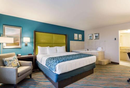 a bedroom with a bed and a chair and a tub at Quality Inn Gulfport I-10 in Gulfport