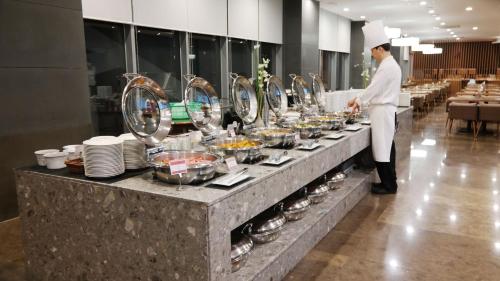 a chef preparing a buffet in a restaurant at Hotel bridge Seogwipo in Seogwipo