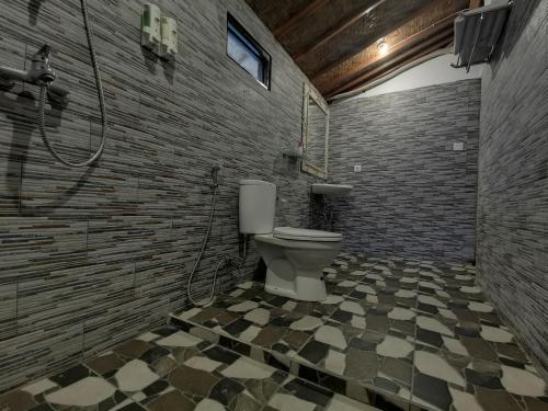 a bathroom with a toilet and a brick wall at Kamasan Cottage in Nusa Penida