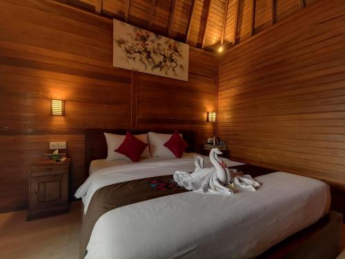 Kamasan Cottage في نوسا بينيدا: غرفة نوم عليها سرير وبجعتين