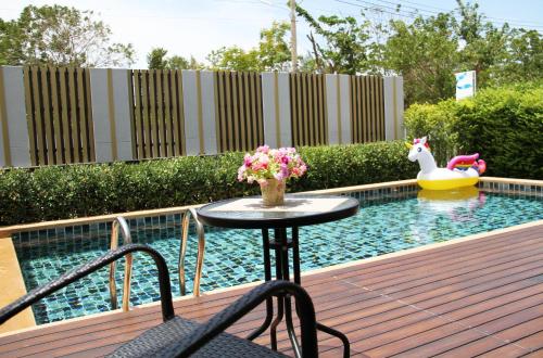 Una mesa con flores en una terraza junto a una piscina. en Thacha Pool Villa A, en Hua Hin