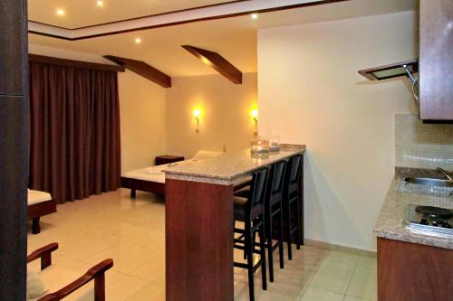 a kitchen with a bar with chairs and a table at 24 Seven Boutique Hotel in Malia