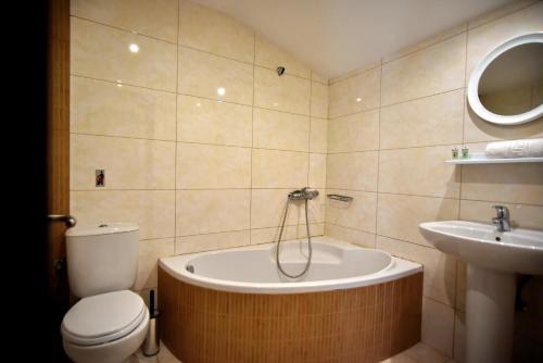 a bathroom with a tub and a toilet and a sink at 24 Seven Boutique Hotel in Malia