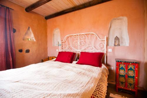 a bedroom with a white bed with red pillows at Hubara Retreat in Charco del Palo