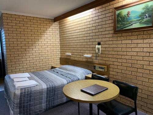 a hotel room with a bed and a table and chairs at Lakeview Motel in Yarrawonga