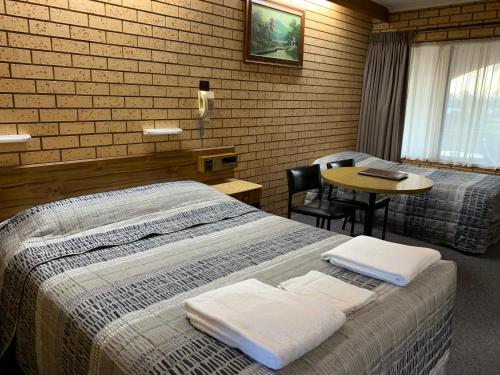 a hotel room with a bed and a table with a chair at Lakeview Motel in Yarrawonga