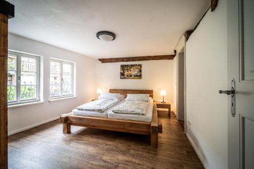 a bedroom with a bed and two windows at Ferienwohnungen Finkenherd 5 in Quedlinburg