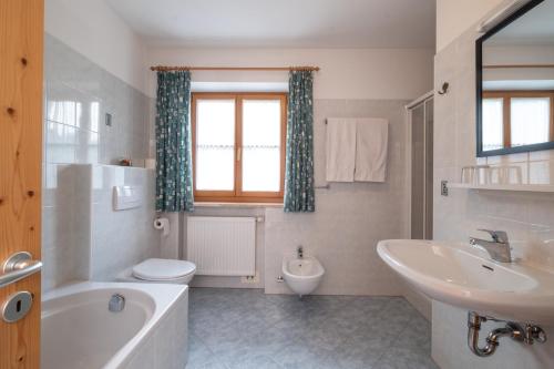 y baño con bañera, lavabo y aseo. en Mantingerhof, en Funes