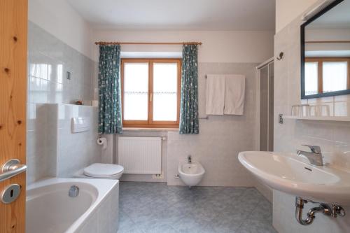 ein Badezimmer mit Badewanne, Waschbecken und Toilette in der Unterkunft Apartments Dolomites "Mantingerhof" in Villnöss