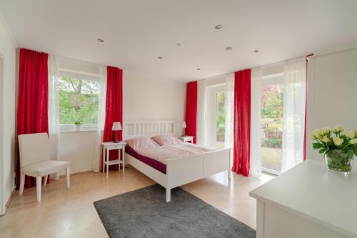 a bedroom with red curtains and a bed and a table at Ferienhaus - Wittenhögen in Buchholz in der Nordheide