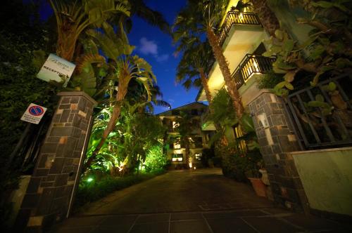 an alley with palm trees and buildings at night at Hotel Borgo Verde in Catania