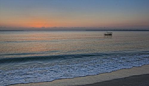 a boat in the water at the beach at sunset at Mediterraneo Boutique Hotel in Dar es Salaam