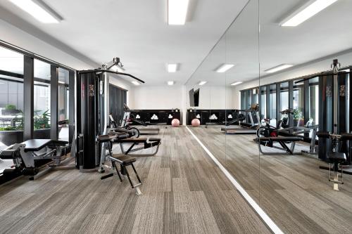 a gym with treadmills and machines in a room with windows at Quest Burwood East in Burwood