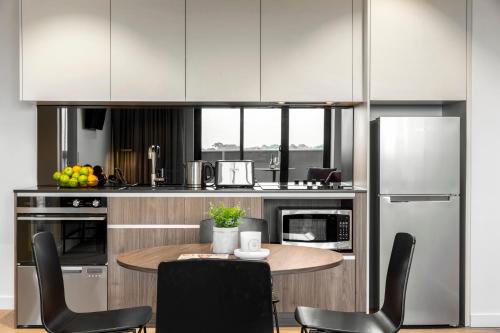 a kitchen with a table and chairs and a refrigerator at Quest Burwood East in Burwood