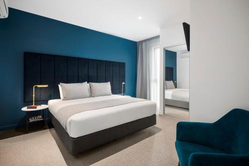 a bedroom with a large bed and a blue wall at Quest Burwood East in Burwood