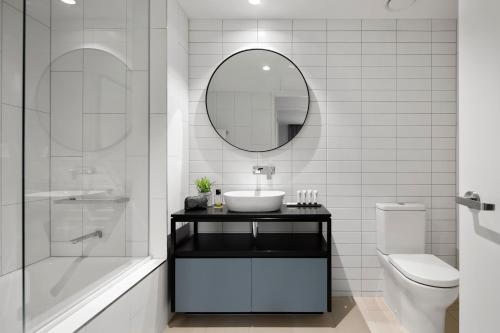 a white bathroom with a sink and a mirror at Quest Burwood East in Burwood